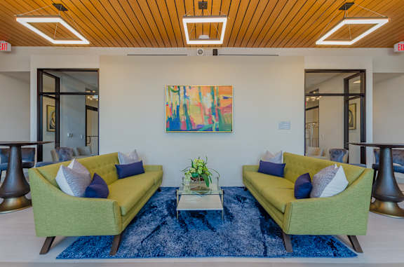Two green couches with blue pillows in a room with a wooden ceiling.