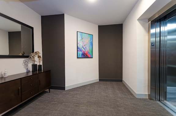 A hallway with a brown cabinet, a mirror, and a painting on the wall.