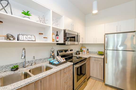 A modern kitchen with a stainless steel refrigerator, a microwave, and a sink.