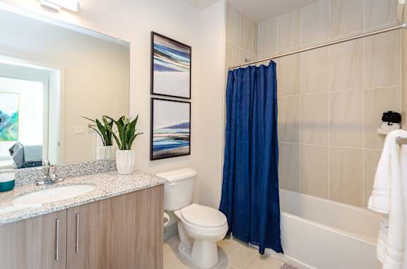 A bathroom with a white toilet, a blue shower curtain, and a white sink.