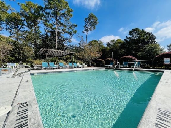 a swimming pool with blue chairs and a resort style pool