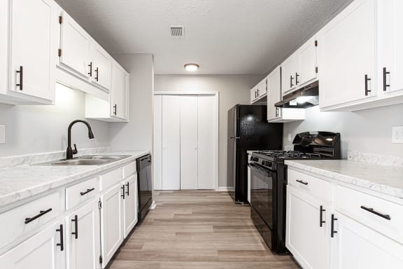 Modern galley style kitchen with white cabinetry at Salem Glen Apartments, Conyers