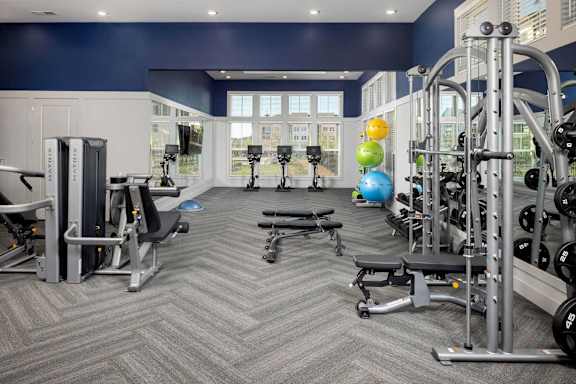 a gym with weights and other exercise equipment and a large window at Century Mundy Mill Apartments, Georgia 30566