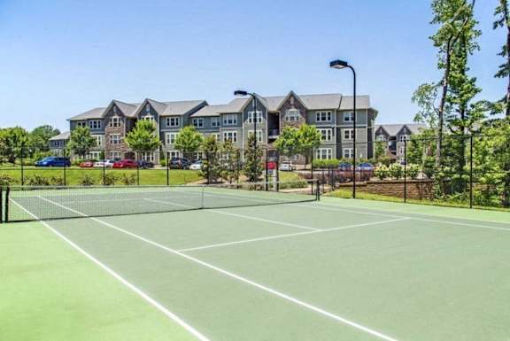 A tennis court in front of a large building.