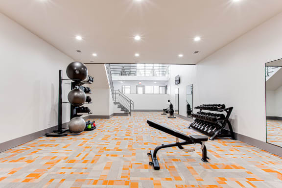 A gym with orange and grey tiles on the floor at The Carter 4250 Apartments, Norcross, GA 30093
