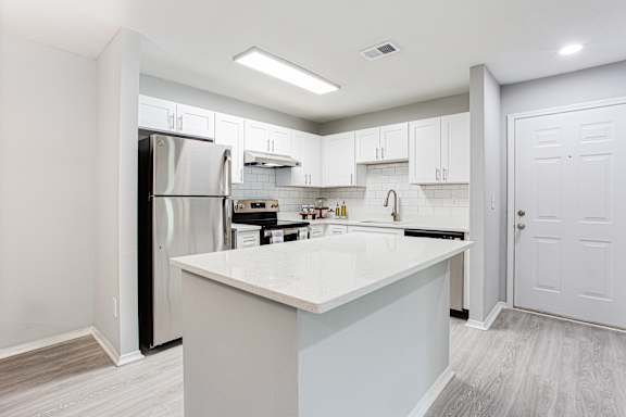 a white kitchen with a large island and stainless steel appliances at Keita 1875, Georgia