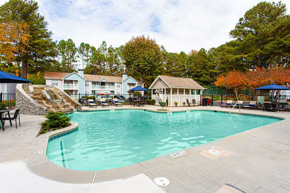 A large swimming pool surrounded by trees and a building in the background at Wildcreek Apartments, Georgia