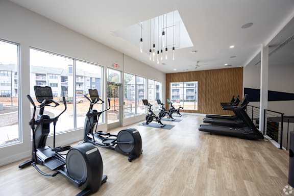 A gym with treadmills, exercise bikes and a wooden floor.