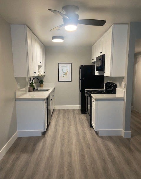 a kitchen with white cabinets and black appliances