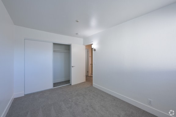 a bedroom with white walls and a door to a closet