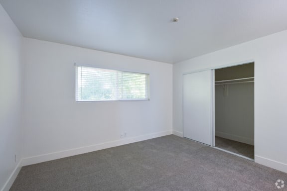 an empty room with a window and a closet