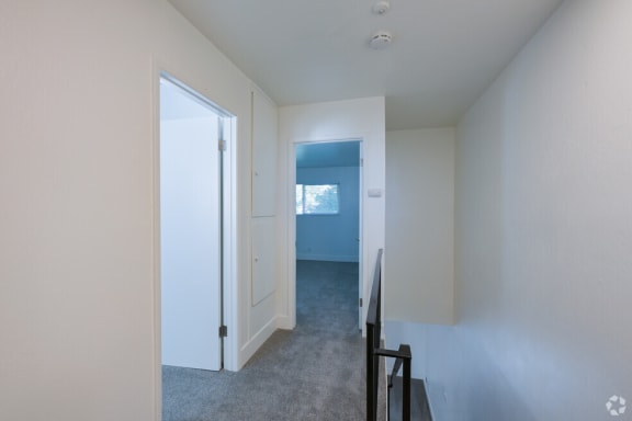 an empty room with a view of a hallway and a door to a bedroom