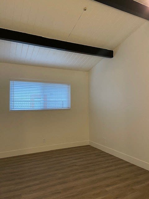 an empty room with a window and wooden floors
