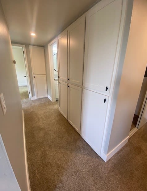 a hallway with white cabinets and a carpet