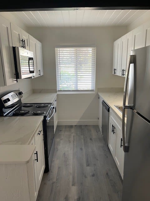 a small kitchen with white cabinets and a window