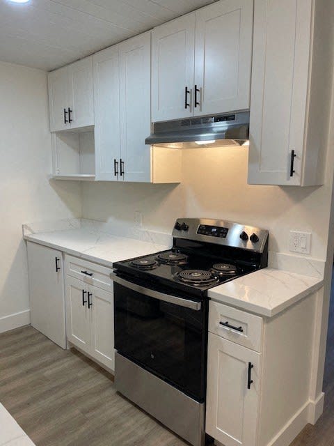 a white kitchen with a black stove and white cabinets
