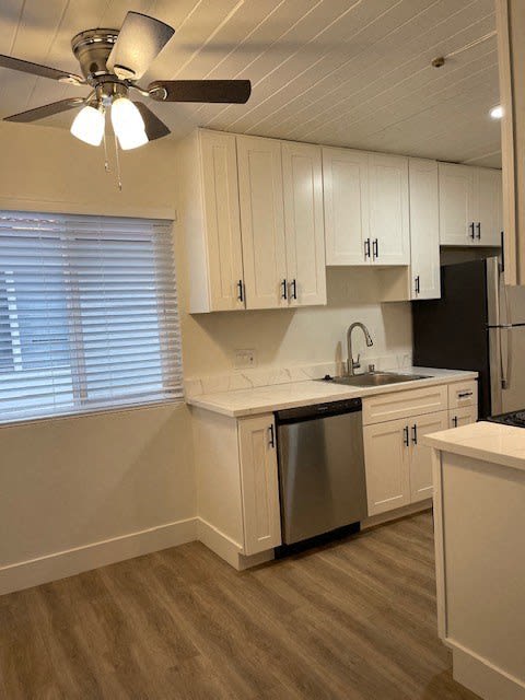 a white kitchen with a ceiling fan and a sink