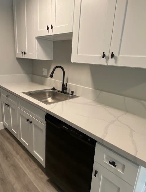 a kitchen with white cabinets and a black dishwasher