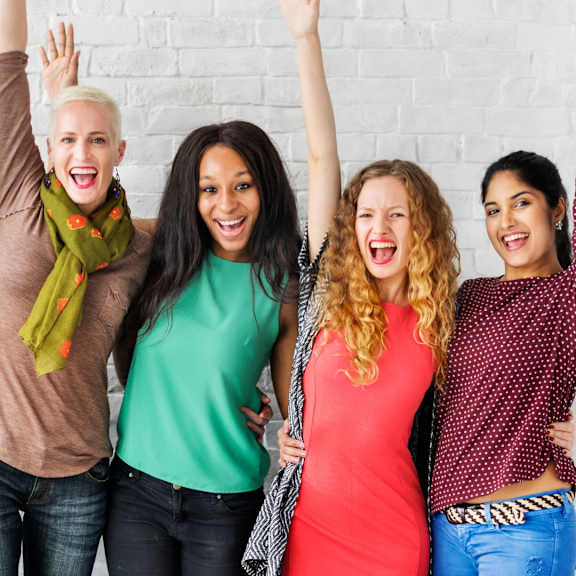 A group of diverse women are holding hands together in a show of unity.