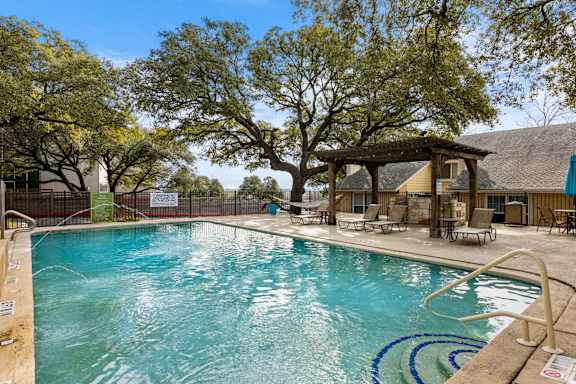 A large swimming pool surrounded by trees and lounge chairs. at The Arbors at Tallwood, Austin