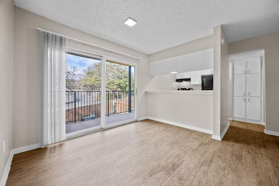 A spacious room with a sliding glass door leading to a balcony.