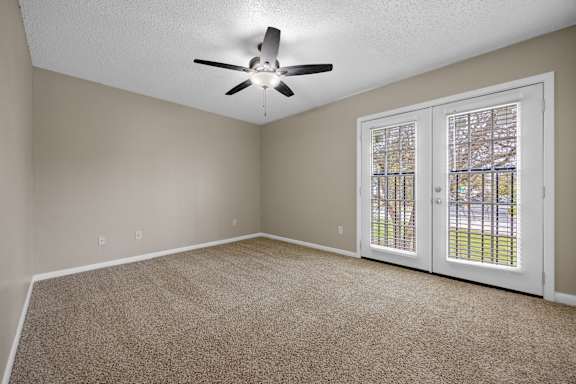 A room with a ceiling fan and carpeted floor.