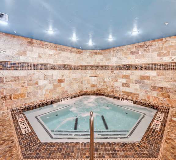 A hot tub in a room with stone walls. at Bridge at Heritage Woods, Austin