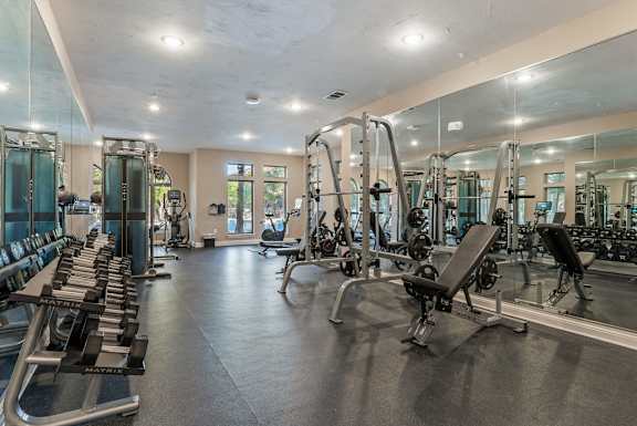 A spacious gym with a variety of equipment including treadmills, weight machines, and free weights. at Bridge at Heritage Woods, Austin, TX, 78753
