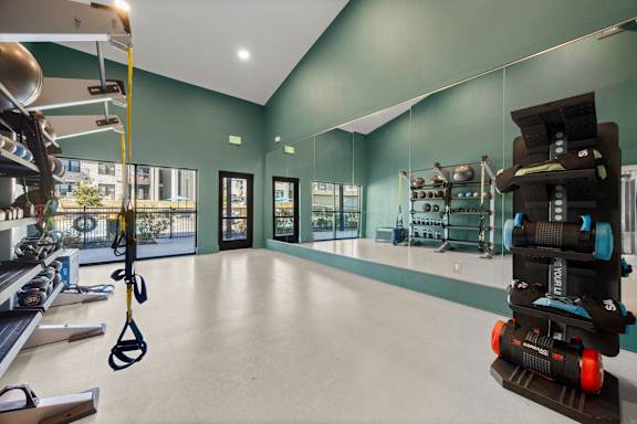 A gym with a green wall and a black and orange exercise bike. at Bridge at Tech Crossing, Austin, 78753