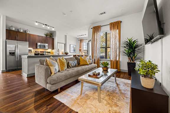 A modern living room with a grey couch and a wooden floor. at The Royce at 8100, Austin