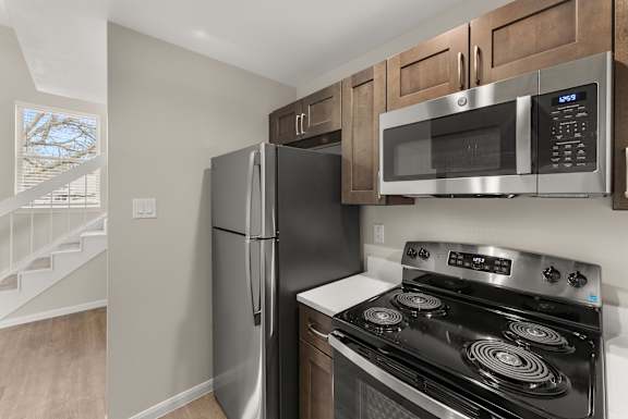 A kitchen with a stainless steel refrigerator, microwave, and stove.