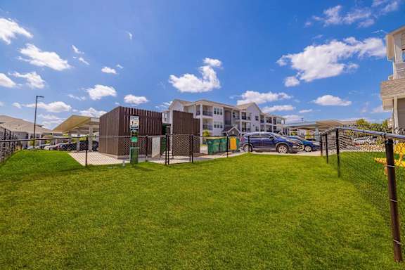 A grassy area with a fence and a building in the background.