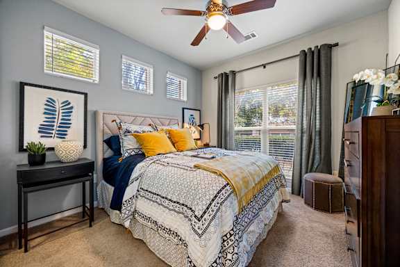 A bedroom with a bed, a ceiling fan, and a window with blinds. at Bridge at Southpark Meadows, Austin, Texas