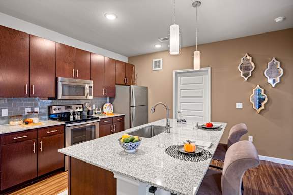 A kitchen with brown cabinets and a granite countertop. at Bridge at Southpark Meadows, Austin, TX