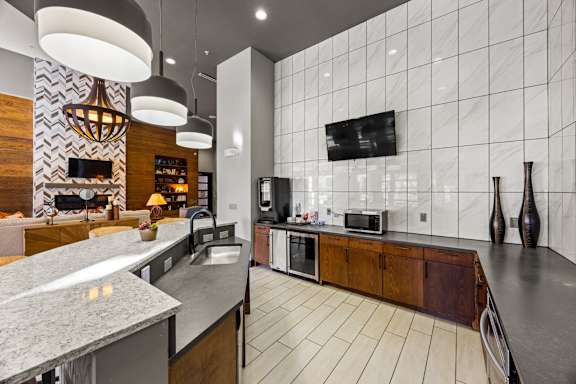 A modern kitchen with a marble countertop and a TV mounted on the wall. at Bridge at Southpark Meadows, Austin, Texas