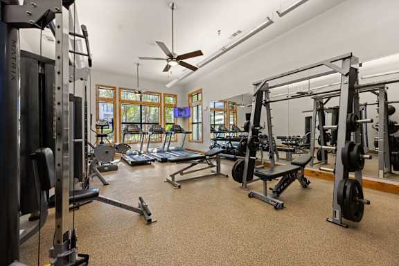 A spacious gym with a variety of equipment and a ceiling fan. at Bridge at Southpark Meadows, Austin, Texas
