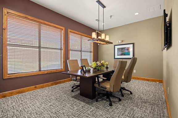 A conference room with a table, chairs, and a television on the wall. at Bridge at Southpark Meadows, Austin