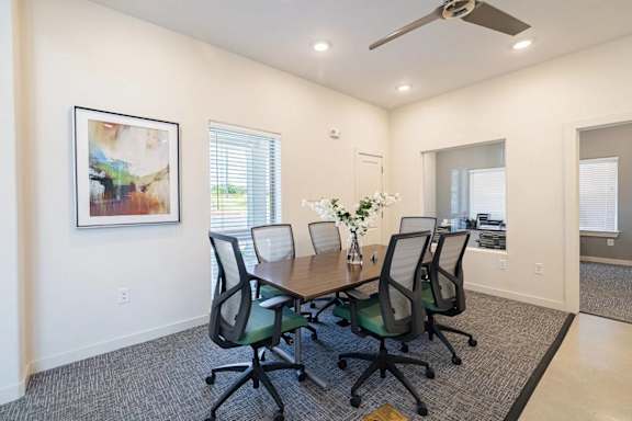 A conference room with a table and chairs and a painting on the wall.