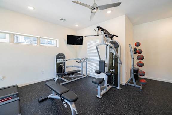 A home gym with a bench, weights, and a television.