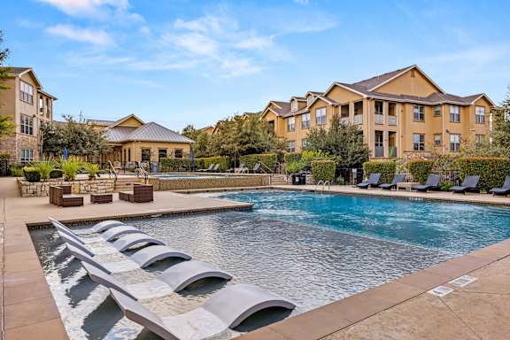 A large swimming pool with lounge chairs in front of apartment buildings. at The James on South First, Austin, Texas
