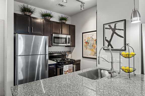 A kitchen with a stainless steel refrigerator and a granite countertop. at The James on South First, Austin, TX