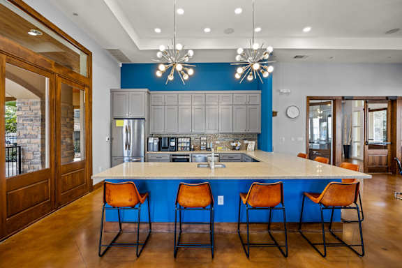 A kitchen with a blue backsplash and a bar area with orange chairs at The James on South First, Austin, 78748.