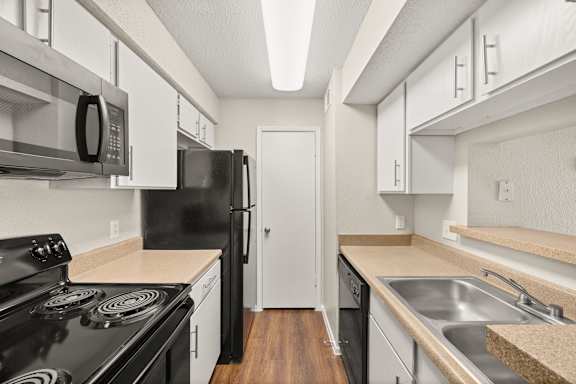 A kitchen with black appliances and white cabinets. at Montecito, Austin, 78741