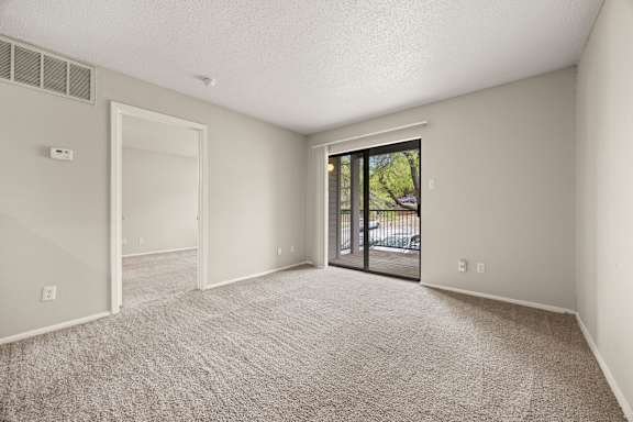 A room with a carpeted floor and a sliding glass door leading outside. at Montecito, Texas, 78741