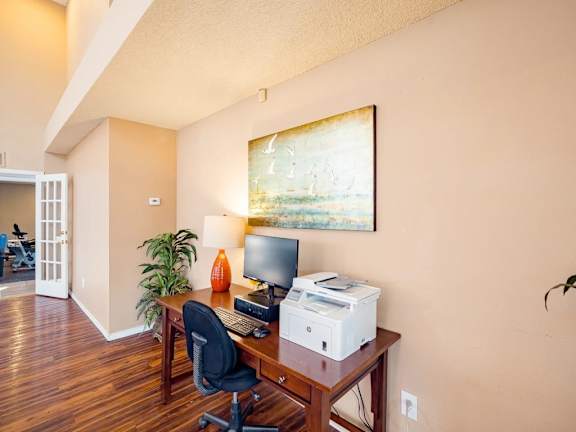 A room with a desk, chair, and a painting on the wall.
