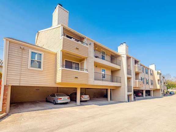 A sunny day at a residential building with cars parked in the garage.