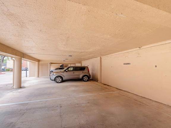 A car is parked in a spacious garage with a white wall and a door labeled "EXIT".