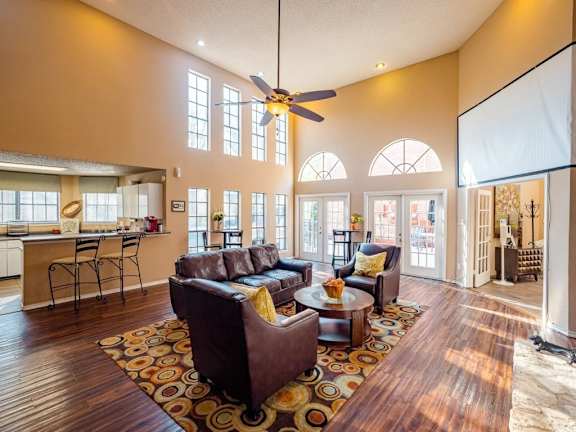 A living room with a brown couch and a ceiling fan.