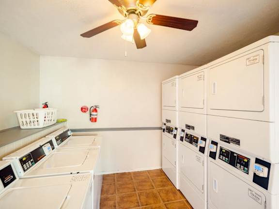 A laundry room with a row of washers and dryers.