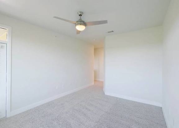 A room with a ceiling fan and carpeted floor.